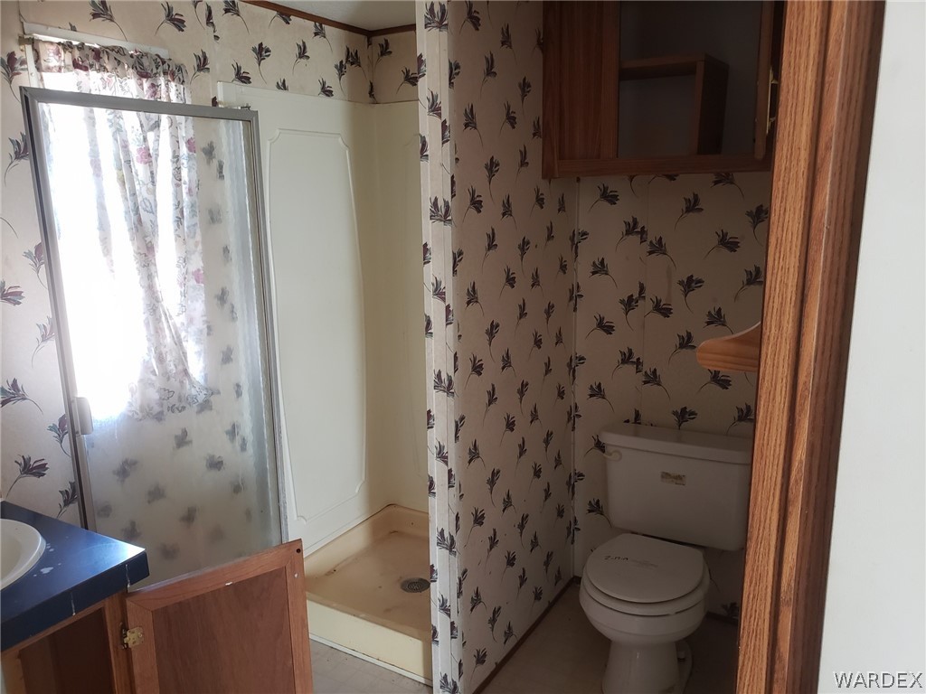 14185 Powerline Road Kingman, AZ 86401 - Photo 7 of 22 a bathroom with a granite countertop toilet a sink and a shower