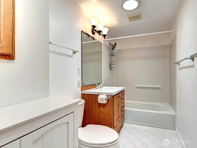 a bathroom with a granite countertop bathtub sink vanity mirror and toilet