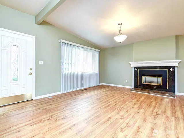 a view of empty room with wooden floor and fireplace