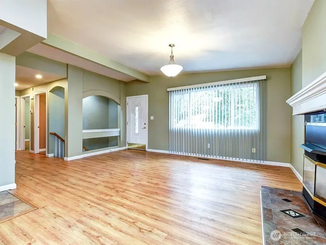 a view of an empty room with kitchen and window