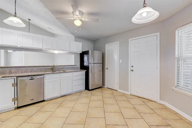 a kitchen with granite countertop a refrigerator a stove a sink and a window