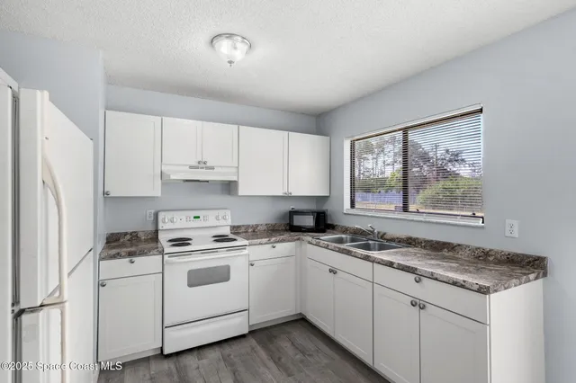a kitchen with granite countertop white cabinets and white appliances
