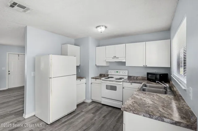 a kitchen with a refrigerator a stove a sink and white cabinets