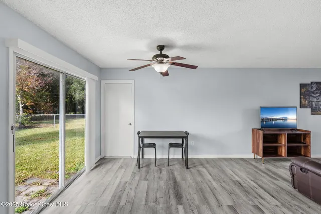 a view of a livingroom with furniture wooden floor fan and a floor to ceiling window