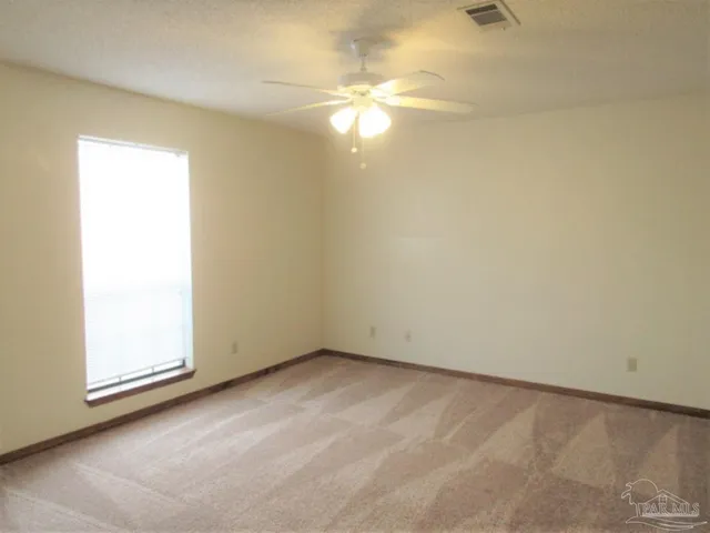 an empty room with a chandelier fan and windows