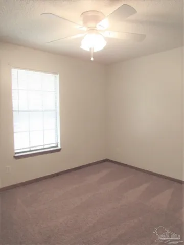an empty room with a window and a fan