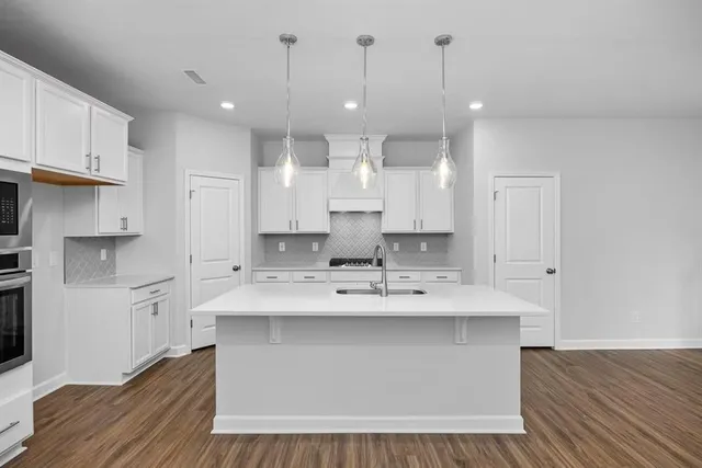 a large white kitchen with kitchen island a sink stainless steel appliances and cabinets