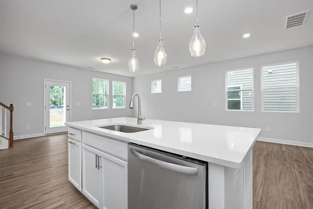 a kitchen with a sink chandelier and wooden floor