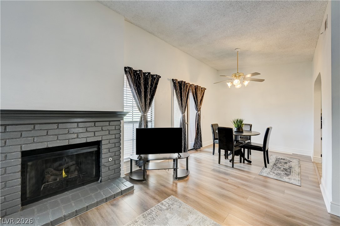 1751 East Reno Avenue, Unit 228 Las Vegas, NV 89119 - Photo 9 of 39 A well-lit interior features a brick fireplace, sleek hardwood floors, and an open layout.