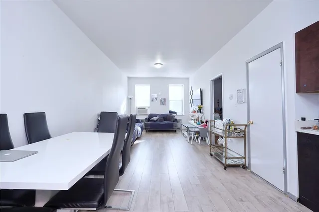 a living room with furniture two large window and wooden floor