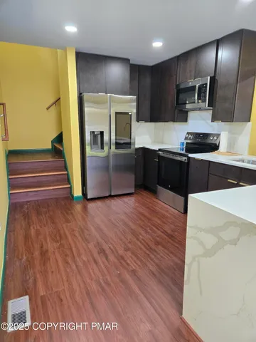 a kitchen with granite countertop a refrigerator and a stove top oven