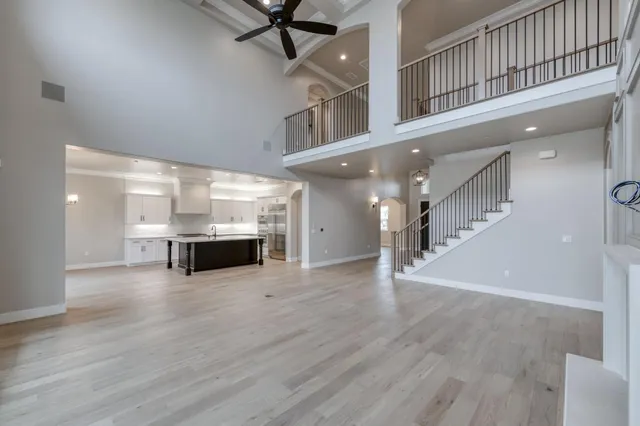 a large white kitchen with a refrigerator a sink dishwasher a dining table and chairs with wooden floor