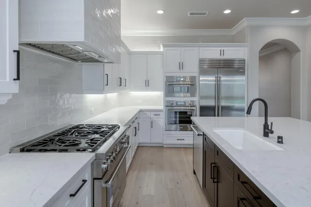 a kitchen with white cabinets and sink
