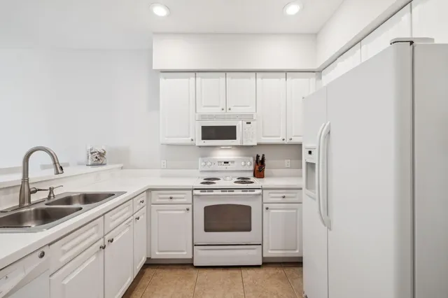 a kitchen with white cabinets white stainless steel appliances and sink