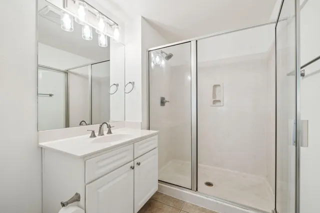 a bathroom with a shower sink vanity and mirror