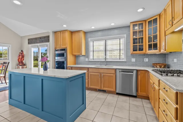 a kitchen with stainless steel appliances granite countertop sink window and chairs