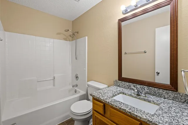 a bathroom with a granite countertop sink a toilet and shower