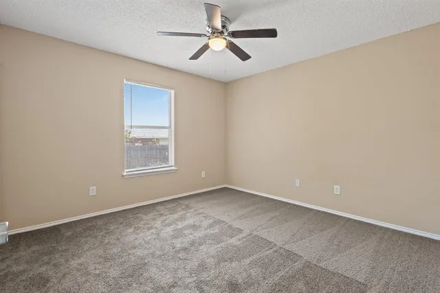 an empty room with windows and fan