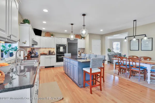 a kitchen with stainless steel appliances granite countertop a refrigerator a sink dishwasher a dining table and chairs with wooden floor