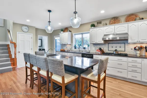 a kitchen with stainless steel appliances granite countertop a stove a sink a dining table and chairs with wooden floor