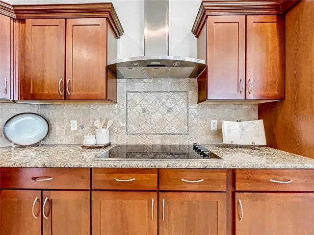 a kitchen with stainless steel appliances kitchen island granite countertop a refrigerator a stove a sink a dining table and chairs with wooden floor