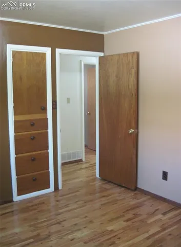 a view of an empty room with wooden floor and closet
