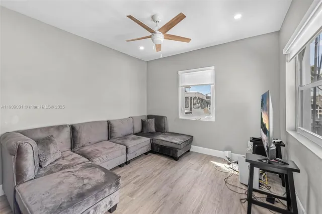 a living room with couches a computer on a desk and a rug