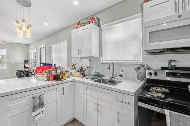 a kitchen with a sink dishwasher stove and white cabinets