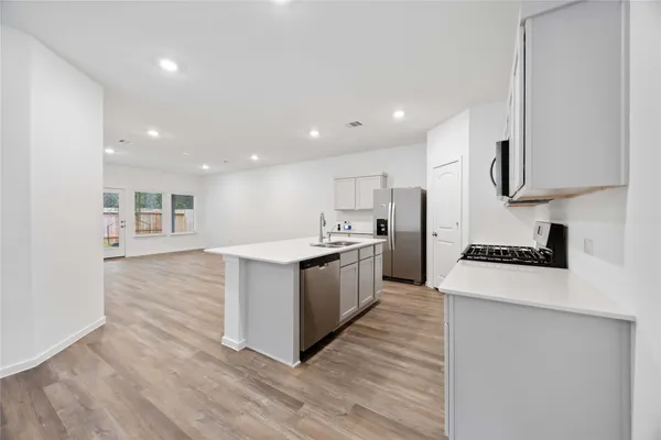 a large kitchen with stainless steel appliances kitchen island a large counter top and a stove top oven