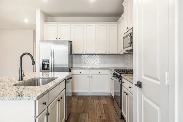 a kitchen with granite countertop a sink stove and cabinets