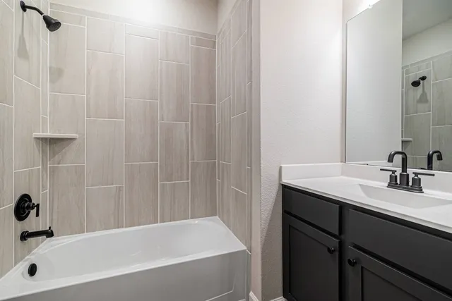 a bathroom with a granite countertop sink a mirror a bathtub and shower