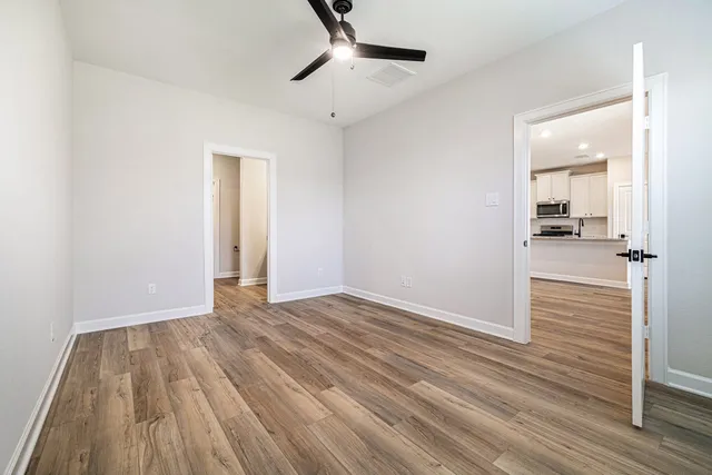 a view of a room with wooden floor and a ceiling fan