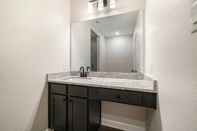 a bathroom with a granite countertop sink and a mirror