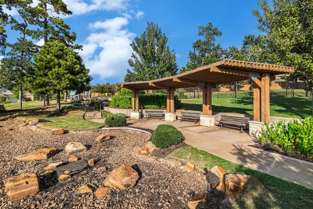 a view of a patio with table and chairs under an umbrella with large trees