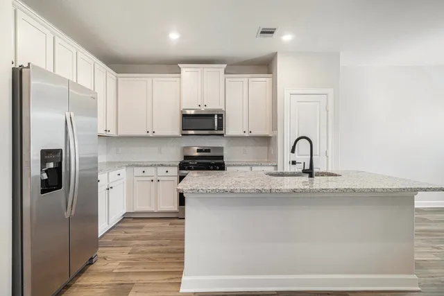 a kitchen with stainless steel appliances granite countertop a refrigerator a stove and a sink