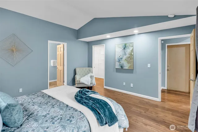 a bedroom with a large bed and wooden floor