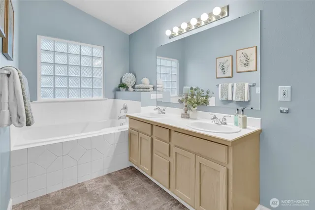 a bathroom with a sink double vanity granite tub and a mirror