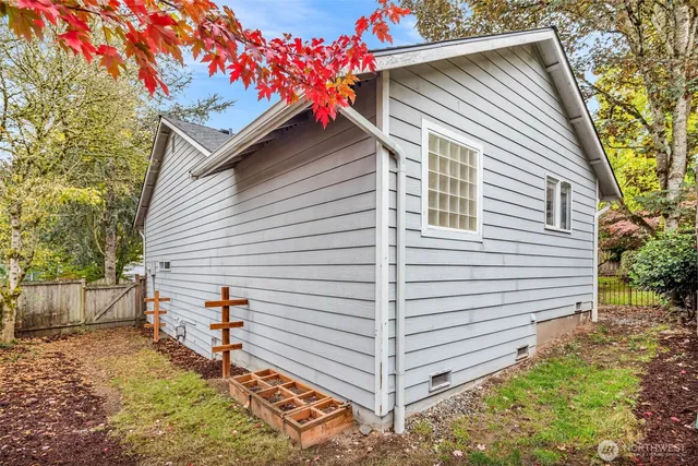 a small white house with a white roof and wooden fence