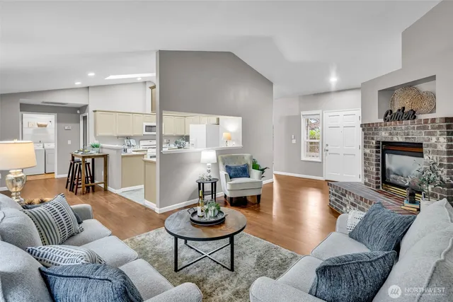 a living room with furniture kitchen view and a wooden floor