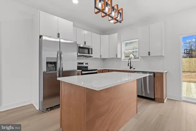 a kitchen with stainless steel appliances granite countertop a sink a stove a refrigerator cabinets and a window