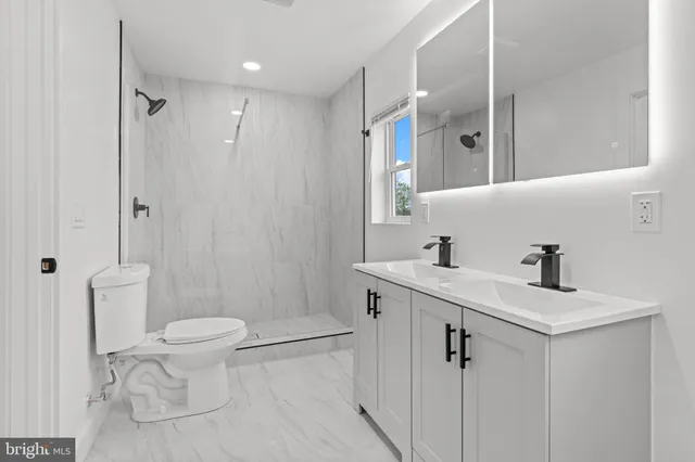 a bathroom with a sink a toilet a mirror and shower