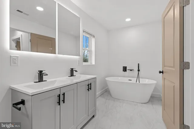 a spacious bathroom with a double vanity sink mirror and a bathtub