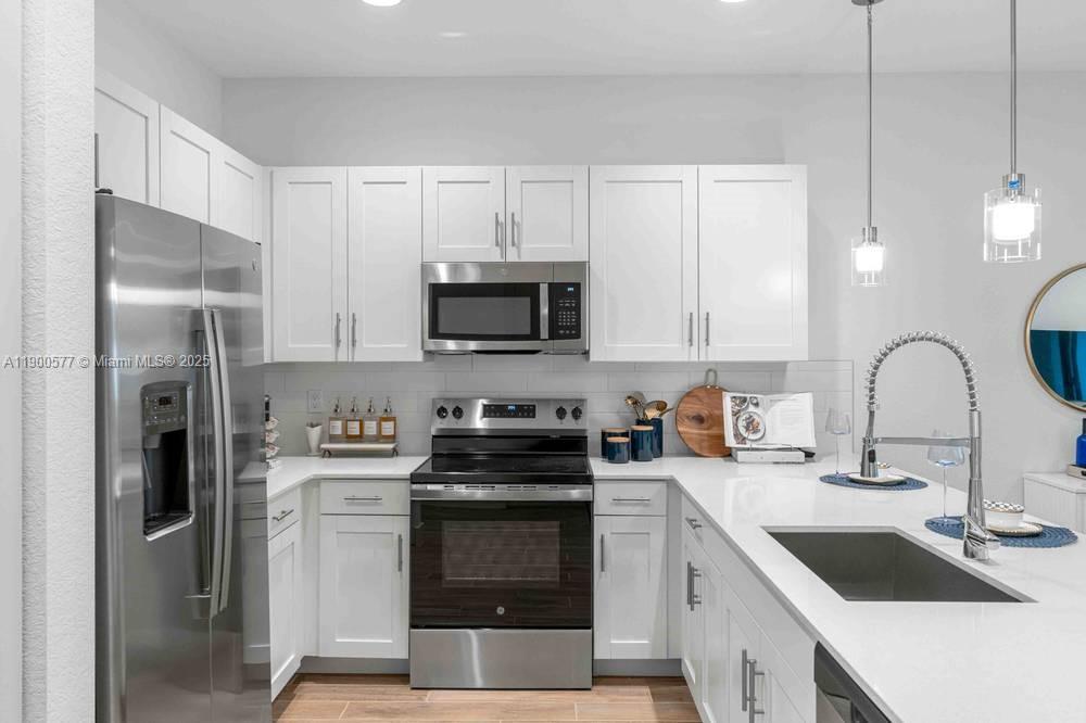 14502 Sloan Rdg Drive, Unit LUMINOSA Delray Beach, FL 33446 - Photo 46 of 49 a kitchen with a sink white cabinets and stainless steel appliances