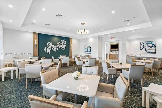 a living room with lots of furniture a rug kitchen view and a large window
