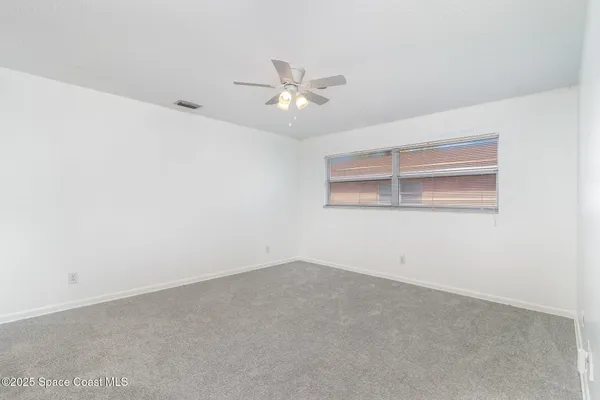 an empty room with a window and ceiling fan