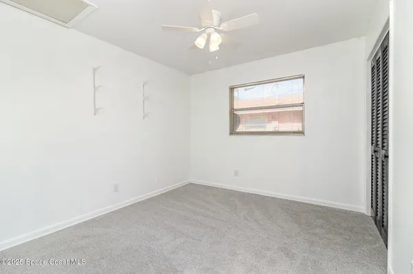 an empty room with a window and a fan
