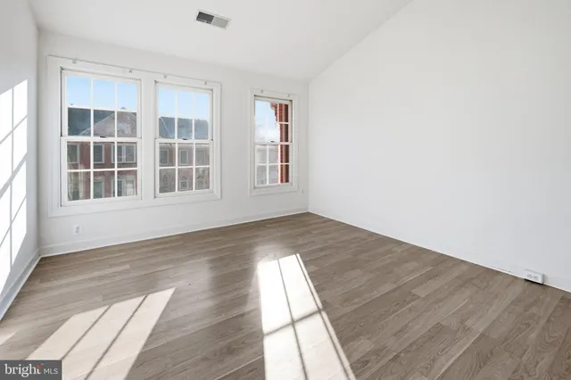 an empty room with wooden floor and windows