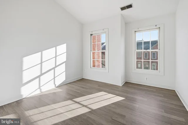 an empty room with wooden floor and windows