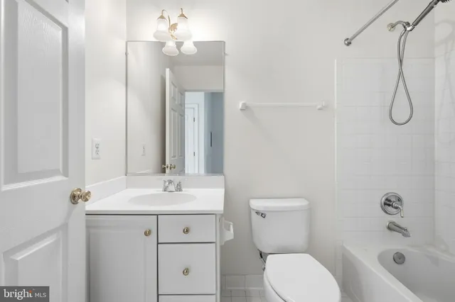 a bathroom with a toilet sink vanity granite and shower