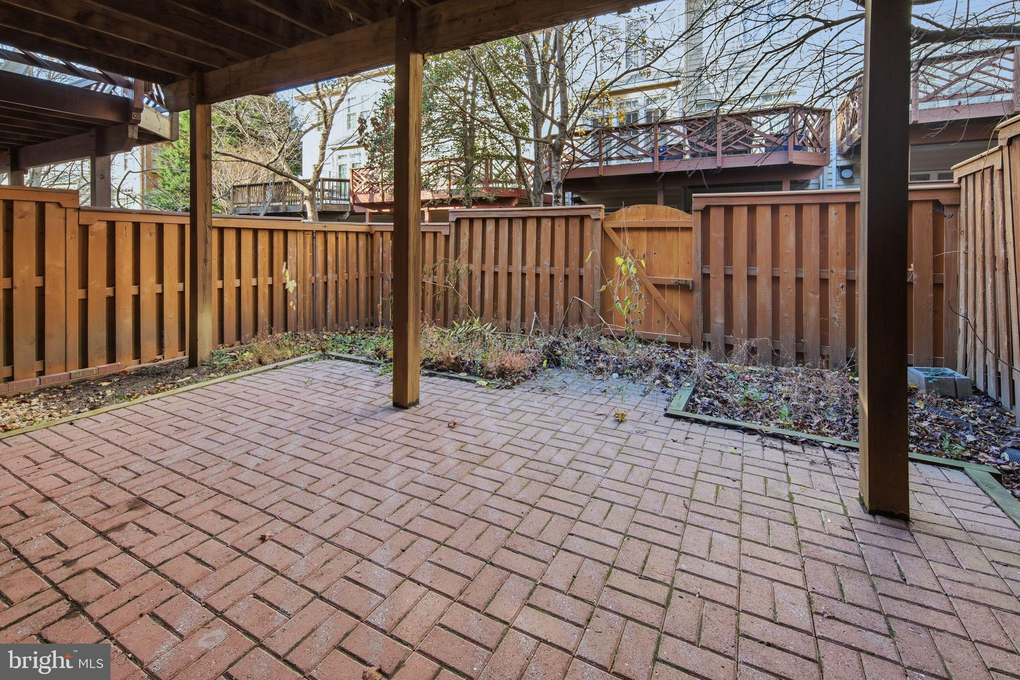 8026 Kidwell Hill Court Vienna, VA 22182 - Photo 22 of 22 a view of a brick house with a small yard and wooden fence